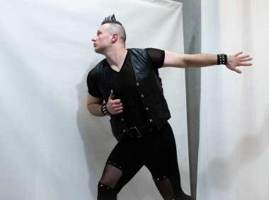 Rock kostümlü bir adam dans figürleri sergiler. Kafasında mohawk olan metal bir adam. Hareket eden adam ve dans eden kollar ve bacaklar..