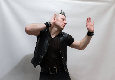 Rock kostümlü bir adam dans figürleri sergiler. Kafasında mohawk olan metal bir adam. Hareket eden adam ve dans eden kollar ve bacaklar..