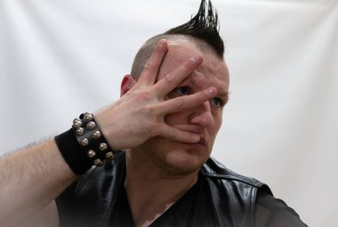 Rock kostümlü bir adam dans figürleri sergiler. Kafasında mohawk olan metal bir adam. Hareket eden adam ve dans eden kollar ve bacaklar..