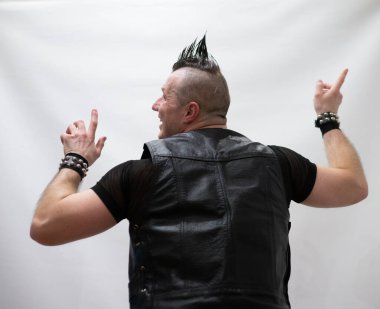 Rock kostümlü bir adam dans figürleri sergiler. Kafasında mohawk olan metal bir adam. Hareket eden adam ve dans eden kollar ve bacaklar..