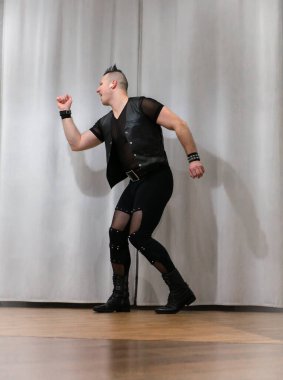 Rock kostümlü bir adam dans figürleri sergiler. Kafasında mohawk olan metal bir adam. Hareket eden adam ve dans eden kollar ve bacaklar..