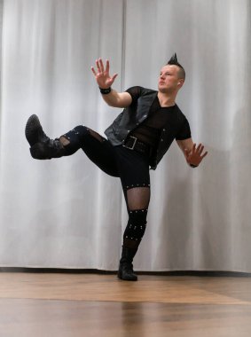 Rock kostümlü bir adam dans figürleri sergiler. Kafasında mohawk olan metal bir adam. Hareket eden adam ve dans eden kollar ve bacaklar..