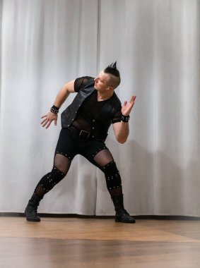 Rock kostümlü bir adam dans figürleri sergiler. Kafasında mohawk olan metal bir adam. Hareket eden adam ve dans eden kollar ve bacaklar..