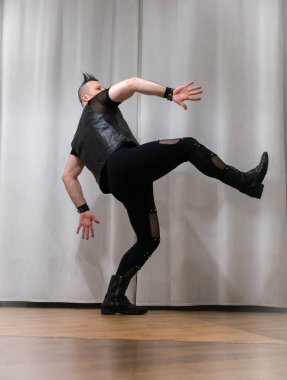 Rock kostümlü bir adam dans figürleri sergiler. Kafasında mohawk olan metal bir adam. Hareket eden adam ve dans eden kollar ve bacaklar..