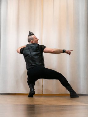 Rock kostümlü bir adam dans figürleri sergiler. Kafasında mohawk olan metal bir adam. Hareket eden adam ve dans eden kollar ve bacaklar..