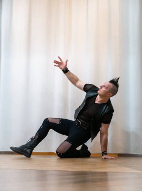 Rock kostümlü bir adam dans figürleri sergiler. Kafasında mohawk olan metal bir adam. Hareket eden adam ve dans eden kollar ve bacaklar..