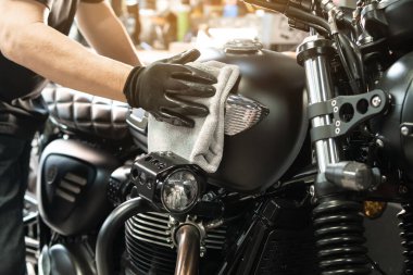 Biker man cleaning motorcycle , Polished and coating wax on fuel tank at garage. repair and maintenance motorcycle concept.