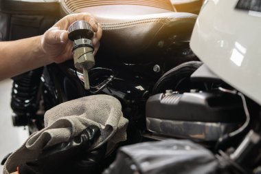 mechanic check engine oil level with oil dipstick on motorcycle or big scooter .maintenance motorcycle concept in garage