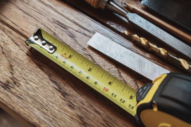 Tape measure with linear-measured markings on wooden background, DIY maker and woodworking concept. selective focus