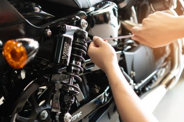 BANGKOK, THAILAN - 28 Şubat 2023: Araç kullanan tamirci Bangkok garajında Harley Davidson motosikletine süspansiyon sıkıştırma ve geri tepme ayarladı