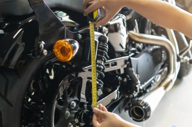 mechanic using tape measure set up suspension sag Compression and Rebound on motorcycle at garage,  repair and maintenance motorcycle concept .selective focus