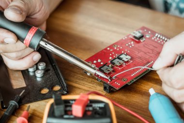 technician man holding iron solder and repairing the circuit board by soldering. electrical work concept .
