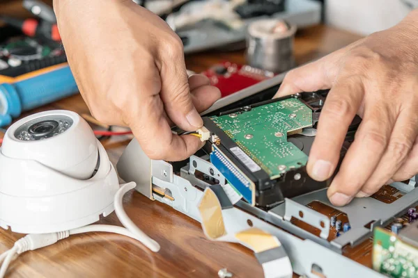 Technician remove a hard disk drive from the CCTV DVR recorder case, to install a new hard drive and upgrading to a Solid State for backup CCTV camera , electrical work and cctv concept