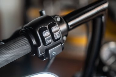 Motosiklet yüksek far anahtarı, düğme kornası düğmeleri ve garajdaki motorsiklet gidonunun sinyalleri, bakım, tamirat, garajdaki motosiklet konsepti.  
