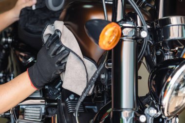 Motosikletli bir motosikleti temizler, garajdaki benzin deposunu cilalar ve cilalardı. tamir ve bakım motosiklet konsepti.