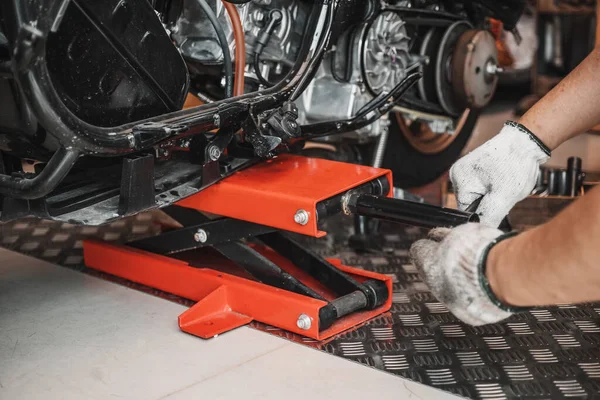 Man use manual Scissor lift jack on a motorcycle , lift the motorcycler with a scissor jack at garage,motorcycle maintenance and repair concept