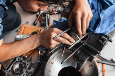 Tamirci garaja bir motosiklet pistonu kuruyor. Motosiklet motorunun sökülmesi ve bakımı