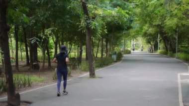 BANGKOK THAILAND, 17 AĞUSTOS 20024 - Şapkalı kadın parkta koşuyor.