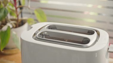 Elektrikli ekmek kızartma makinesinden çıkan dilimlenmiş ekmeği ahşap masaya yakın tut. 