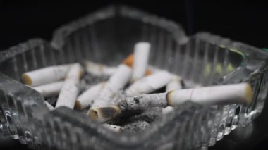  Sigara kültablasında yanan sigaralar, sigara içmenin sizi kanser, felç ve diğer sağlık sorunları riskine soktuğu kavramı..