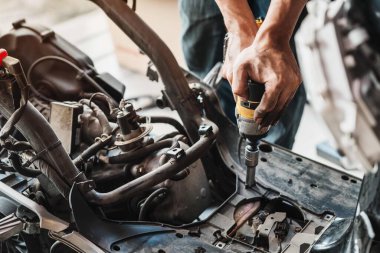 Motosiklet tamircisi garajda motorsiklet tamir etmek için elektrikli tornavida ve elektrikli alet kullanır.