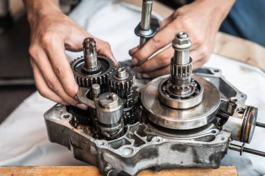 Motosiklet tamircisi bir motorun tamirinde çalışıyor, garajda çalışıyor, bakım yapıyor, motosiklet konseptini tamir ediyor.