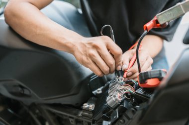 Motosiklet tamircisi motorsiklet elektrik sistemini kontrol etti. Çoklu metre kullanarak elektrik tesisatı sorunu buldu. Garajda çalışmak, motosiklet tamir konsepti , 