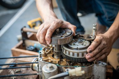Motosiklet tamircisi bir motorun tamirinde çalışıyor, garajda çalışıyor, bakım yapıyor, motosiklet konseptini tamir ediyor.