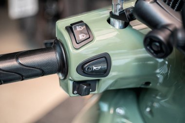 Gidonlu motorsiklet kornası düğmesinin yakın görüntüsü, düğme kontrolleri ve güvenlik ile ilgili bir motosikletin anahtarları.