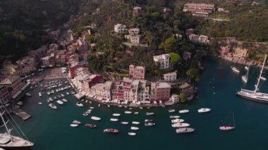 Portofino Körfezi 'nin güneşli, güneşli bir günde, birçok lüks yat ve zümrüt suyuyla çekilmiş insansız hava aracı görüntüsü.