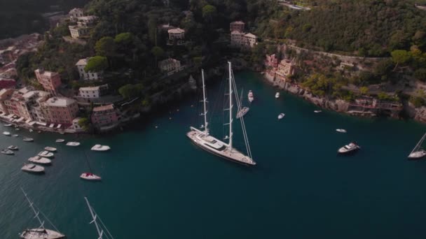 イタリアのポルトフィーノ近くの湾に滞在する大きなセーリングヨットの空中ドローンショット 崖とイタリア風の家で崖に囲まれた崖 — ストック動画