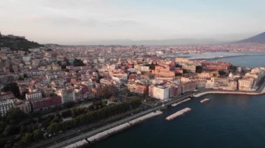 Napoli, İtalya 'nın nefes kesici hava manzarası. Tarihi binalar ve gün batımında çarpıcı rıhtım. Canlı mimari, ağaçlarla kaplı sokaklar ve sakin Napoli Körfezi..