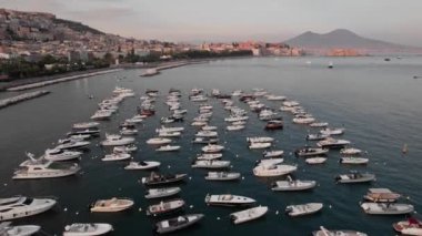 İtalya, Napoli 'nin sakin bir limanında bulunan ve arka planda kıyı kenti bulunan sayısız teknenin sakin hava manzarası. Vezüv Dağı berrak bir gökyüzünün altında görünür..