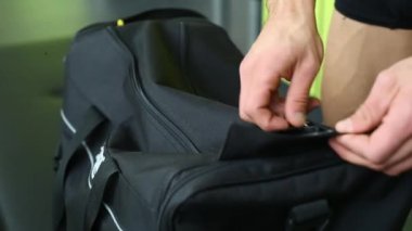 Handsome man taking bottle from sports bag in locker room