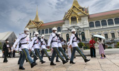 BANGKOK, THAILAND 30 Nisan 2023 beyaz cüppeli nöbetçiler vardiya değişimi için devriye geziyor. Gündüz vakti ışık alan Büyük Saray 'da..