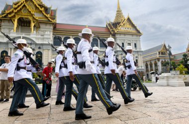 BANGKOK, THAILAND 30 Nisan 2023 beyaz cüppeli nöbetçiler vardiya değişimi için devriye geziyor. Gündüz vakti ışık alan Büyük Saray 'da..