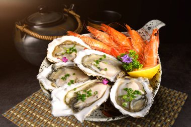 Japon usulü arkaplanda limonlu taze istiridye ve karidesler.