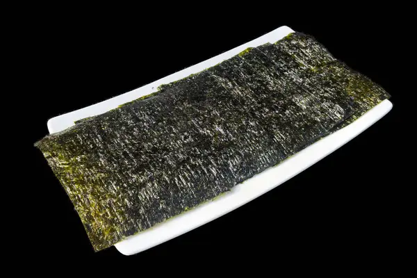 Beyaz dikdörtgen seramik bir tabağa yerleştirilmiş siyah bir arka planı olan gevrek kurutulmuş Norveç yosunları..