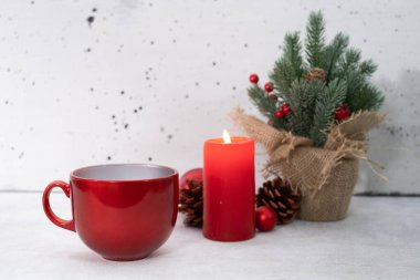 Beyaz tozlu beton zemin üzerinde kırmızı kış çay fincanı artı mum, çam, küçük ağaç - manzara