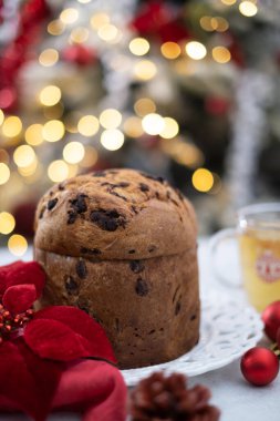Çikolata parçacıklı Panettone ve kırmızı topları ve bokeh arkaplanlı beyaz masada bir fincan çay. Yüksek kalite fotoğraf