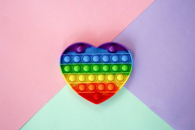 Renkli anti-stres duyusal renkli oyuncak, kalp şeklinde, renkli karton arka plan