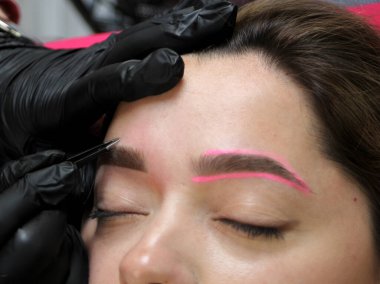 Kozmetik uzmanı, kuaförde çalışan bir müşteriye kaş makyajı yapıyor. Mikroplanma tekniği..