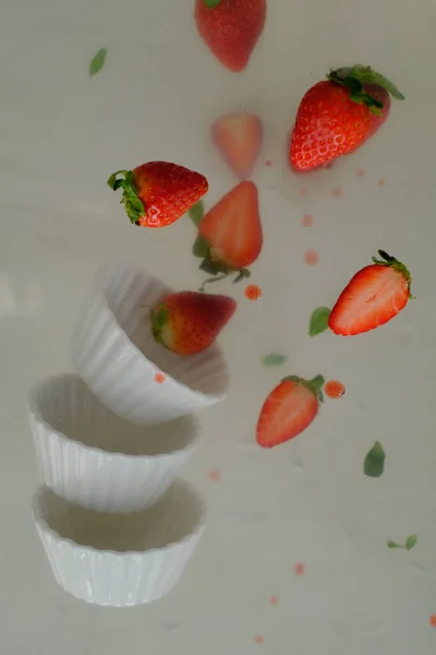 Strawberries in white bowls levitating on the air. Rule of thirds applied
