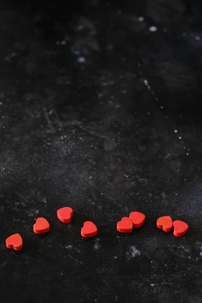 Red small hearts on dark background, creative layout