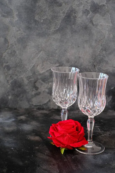 Two beverage glasses with a red roseon a dark background. Minimalist style photography, Romantic dinner. Love. Couple.