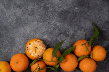 Top view of tangerines with green leaves on a dark background. Negative space. Space for writing 