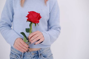 Beautiful and attractive woman dressed in baby blue holding a red rose in her hands. Self love concept. Happy. Copy space.