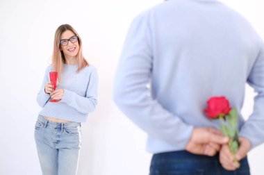 Young attractive man holding a rose behind his back to surprise his lover. Love celebration concept. Date concept. Surprise for her. Happy couple. Elegance. Love. Attraction