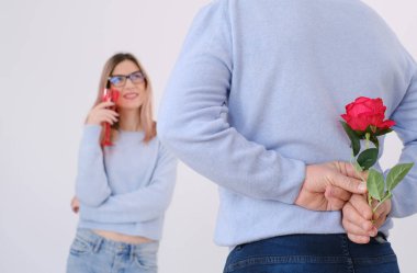 Young attractive man holding a rose behind his back to surprise his lover. Love celebration concept. Date concept. Surprise for her. Happy couple. Elegance. Love. Attraction
