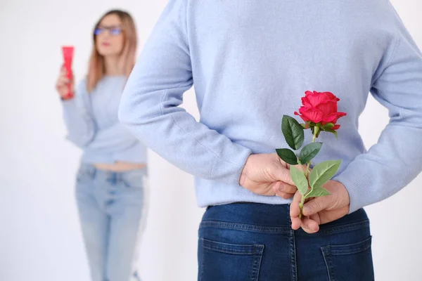 Young attractive man holding a rose behind his back to surprise his lover. Love celebration concept. Date concept. Surprise for her. Happy couple. Elegance. Love. Attraction